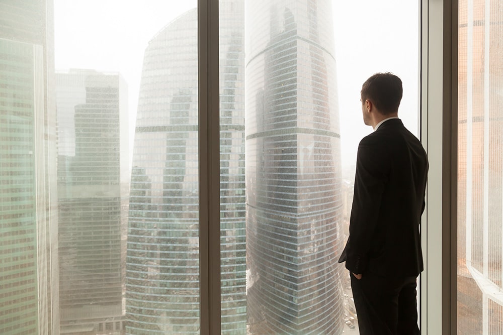 company-official-looking-through-window-office-min